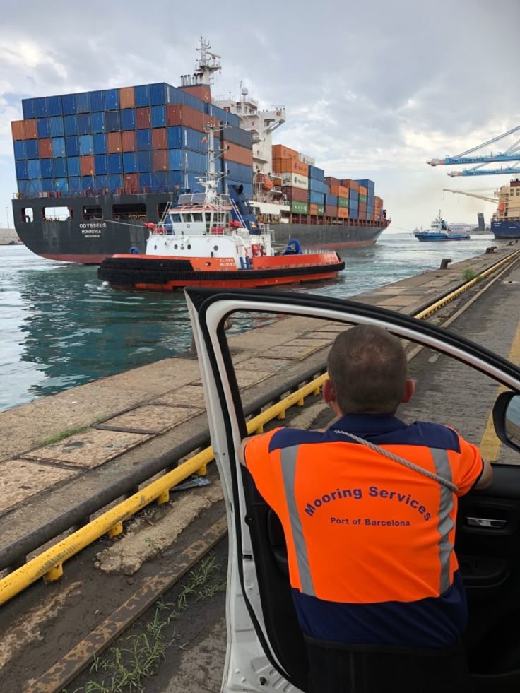 Mooring crew watching a container ship escorted by a tug